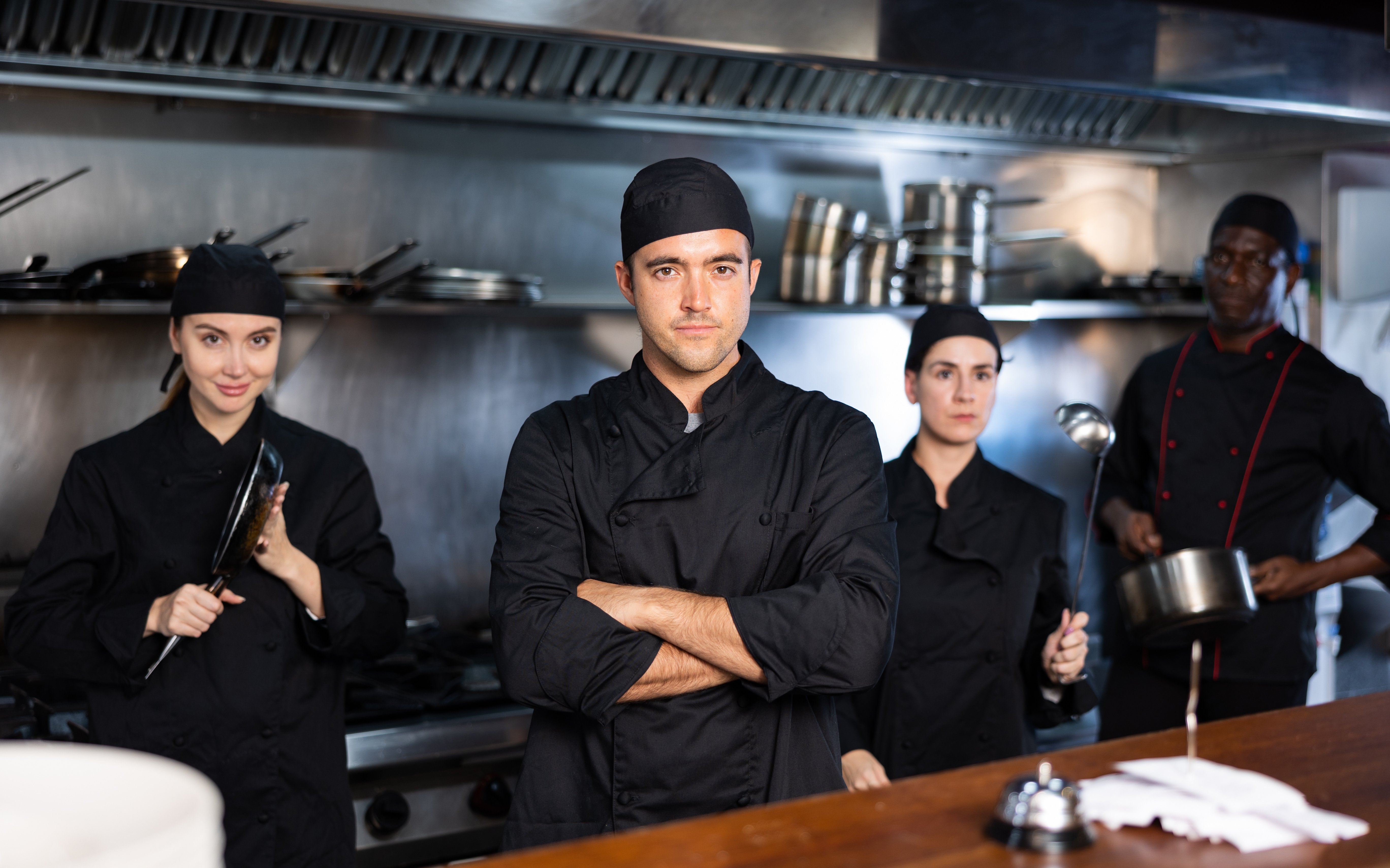 Four workers stand in a restaurant kitchen. 